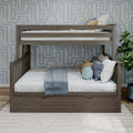Gray-washed wooden twin-over-twin bunk bed in a modern kids' bedroom with blue geometric wallpaper, white and blue bedding, decorative pillows, under-bed storage drawer and potted plant