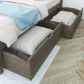 Gray wood trundle bed with under-bed storage drawers, white quilted mattresses and light blue throw blanket in bedroom interior