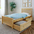 Twin wooden bed with pull-out trundle storage and blue polka-dot bedding, fiddle-leaf plant and framed botanical prints in a bright modern bedroom
