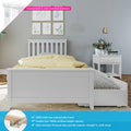 White wooden kids bed with pull-out trundle, yellow polka-dot duvet, white bedside table with vase, gold pendant light and framed botanical prints on gray wall