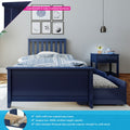 Navy blue kids trundle bed with pull-out mattress and 100% solid New Zealand pine frame, matching blue nightstand, striped bedding, sports-themed framed wall art and pendant lamp in modern children's bedroom