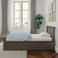 Minimalist bedroom interior with wooden storage bed, light-blue polka-dot duvet, potted plants on windowsill, fiddle-leaf fig, neutral curtains and framed animal art