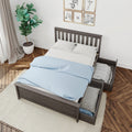 Modern gray wooden bed frame with under-bed storage drawers, blue polka-dot duvet and white pillows in styled bedroom with potted plant, gallery wall and herringbone wood floor