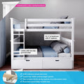White twin-over-twin kids bunk bed with ladder, built-in storage drawers, safety rails and blue-gray bedding on a solid pine frame