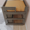 Top-down view of a gray wood bunk bed with orange fitted sheet, hardwood floor and striped area rug in a modern kids' bedroom