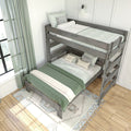 Gray wooden bunk bed with green and white bedding, decorative pillows, patterned rug and sheer curtains in a bright kids bedroom