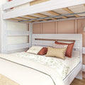 Whitewashed wooden bunk bed with exposed slatted mattress support and metal rail, floral duvet and rust-colored decorative pillows on lower bed in modern bedroom