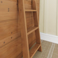 Close-up of natural wood loft ladder mounted on horizontal wood paneling with visible screw fasteners, beige trim and woven rug