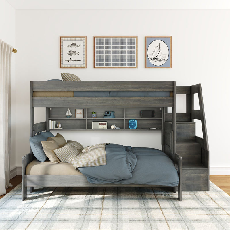 Gray wooden bunk bed with staircase storage and built-in shelves, lower full-size bed with blue bedding, nautical wall art and plaid rug in a bright kids' bedroom