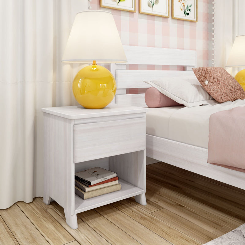 White wooden nightstand with drawer and open shelf holding books, yellow spherical table lamp beside white bed with pink pillows and bedding on hardwood floor