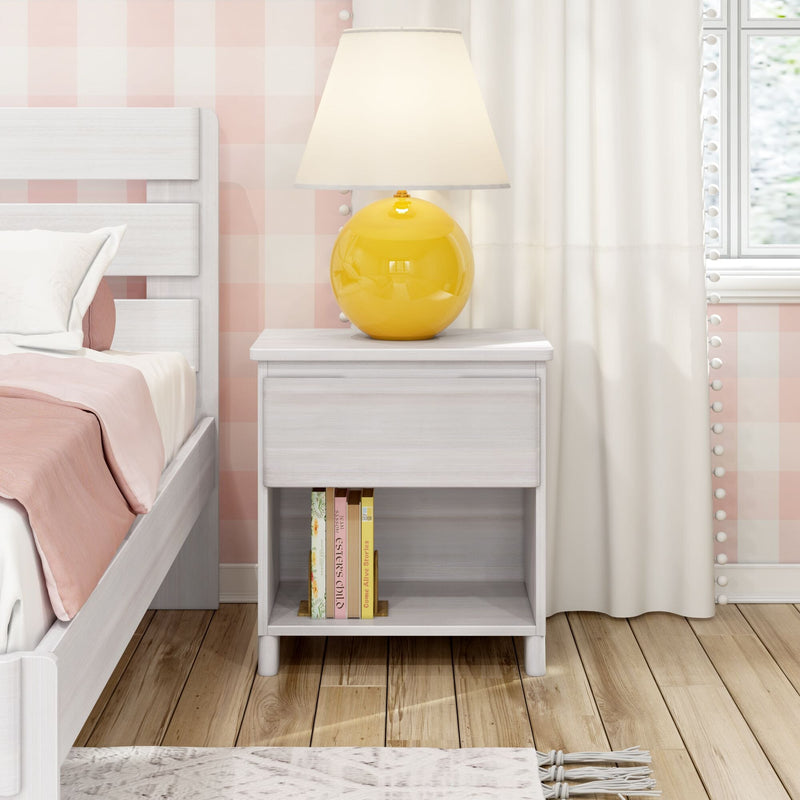 White wooden nightstand with yellow ceramic table lamp, pink bedding, pastel gingham wallpaper, stacked books and hardwood floor in a bright modern bedroom decor
