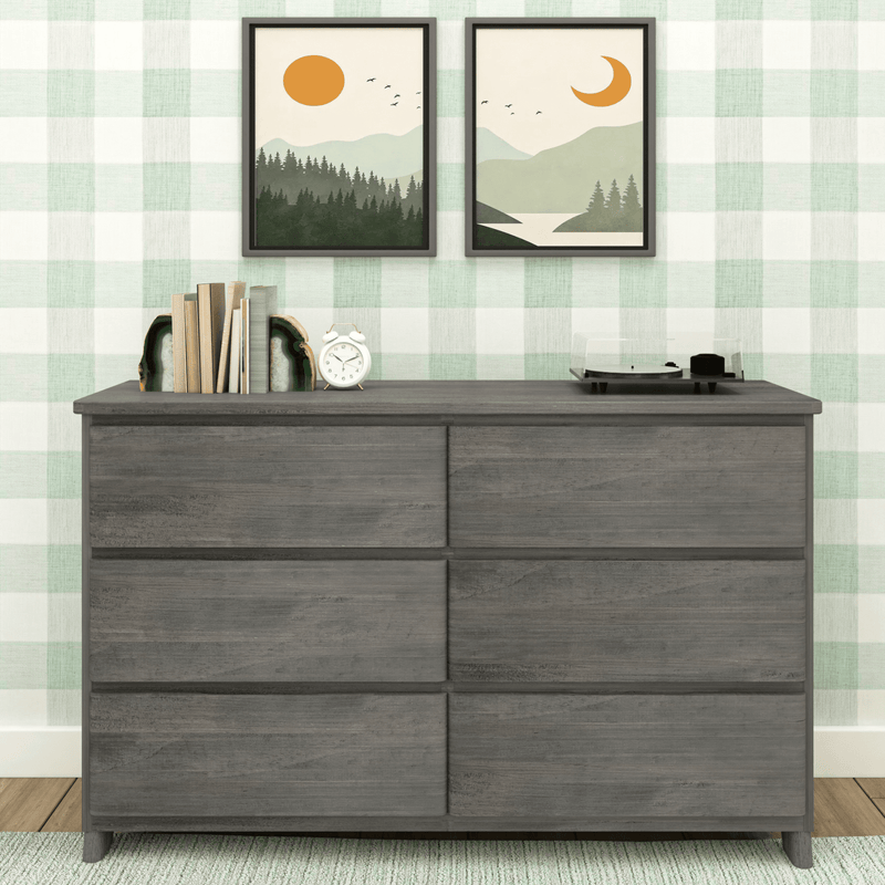 Gray six-drawer wood dresser styled with books and agate bookends, white alarm clock and record player against mint green gingham wallpaper and framed landscape prints, modern farmhouse bedroom dresser