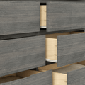 Close-up of modern gray wood dresser with multiple partially open drawers revealing light natural wood interiors and folded linens, ideal bedroom storage and organization
