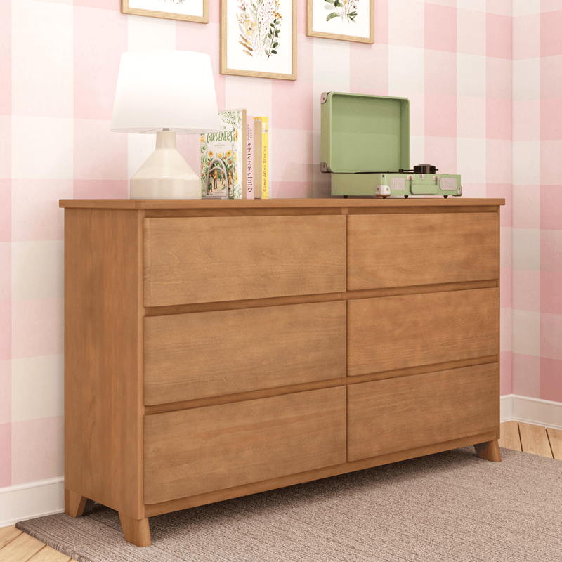 Six-drawer oak dresser in pink checkered nursery with lamp, children's books, floral wall art and green record player
