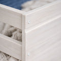 Close-up of whitewashed wooden storage crate corner with slatted panels, visible screw and natural wood grain