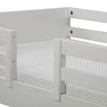 Close-up of white wooden bed guard rail and textured mattress cover on a modern bunk bed frame, nursery safety rail detail