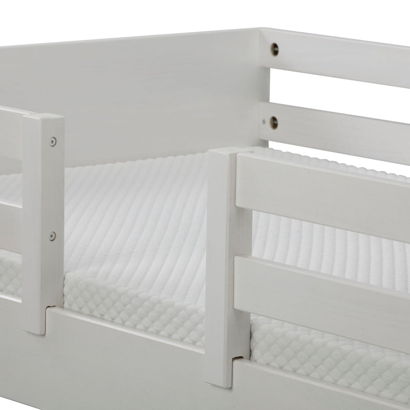 Close-up of white wooden bed guard rail and textured mattress cover on a modern bunk bed frame, nursery safety rail detail
