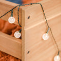 Globe string lights draped over natural wood frame creating warm outdoor patio lighting for deck, pergola, or backyard ambiance