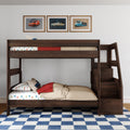 Dark wood children's bunk bed with built-in storage stairs, car-print sheets and pillow, beige comforter with red throw, blue checkered rug and three framed vintage car posters on white wall