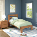 Cozy child's bedroom with navy blue paneled walls, wooden twin bed with mint green bedding, nightstand lamp, framed yellow floral art, sunlit window and wooden toy train on a blue plaid rug