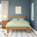 Cozy modern bedroom with blue vertical paneled wall, wooden bed and light green bedding, bedside lamp and nightstand, framed yellow floral art and wooden toys on a blue-check rug