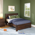 Kids bedroom with sage green shiplap walls, dark wood platform bed with navy bedding and green pillows, framed cowboy print, bedside lamp, wooden toys on rug and sunlit window