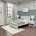 Cozy modern bedroom with light wood bed, sage green wainscoting, botanical wallpaper, black-framed window, neutral curtains and bedside lamps