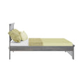 Side view of modern gray wooden bed frame with light green linens, textured throw blanket and pillows on a white background