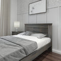 Modern neutral bedroom with gray wooden bed frame, white-and-gray bedding, bedside lamp, nightstand, gray curtains and dandelion wall art