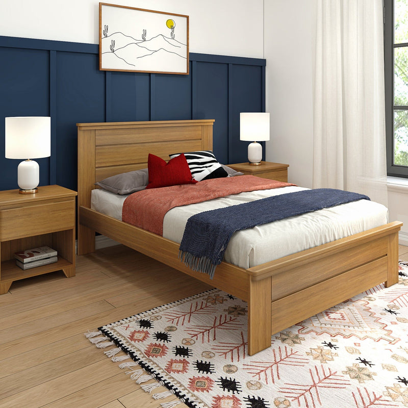 Modern bedroom with navy board-and-batten accent wall, oak platform bed, white bedside lamps, red accent pillows and patterned boho rug