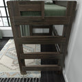 Dark wood bunk bed close-up showing ladder and guardrail, green bedding, patterned rug and window in a modern bedroom