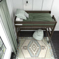 Dark wood loft bed with green bedding, patterned area rug, pale green curtains and beanbag in a cozy modern kids' bedroom