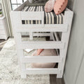 Whitewashed wooden loft bed with striped bedding, pink decorative pillows and built-in ladder in modern farmhouse kids bedroom