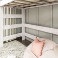 Whitewashed wooden bunk bed frame in a neutral children's bedroom with beige curtains, textured rug and pink pom‑pom pillow