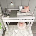 White wooden loft bed with black-and-white striped bedding, pink pom-pom and boho throw pillows, cozy kids' reading nook with round beanbag, patterned rug and wall sconce