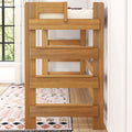 Solid wood bunk bed frame with safety rail and ladder in bright bedroom featuring patterned area rug and hardwood floor