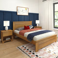 Modern bedroom with oak bed and nightstands, navy blue paneled accent wall, white bedside lamps, cozy red and gray bedding, minimalist framed art and patterned boho rug