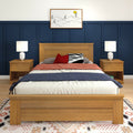 Modern bedroom with wooden bed frame, navy blue wainscoting, matching nightstands and lamps, red and zebra accent pillows, minimalist framed wall art and patterned area rug