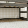 Gray weathered wood loft bed frame with ladder and slatted mattress platform above hardwood floor and neutral plaid wallpaper in children's bedroom