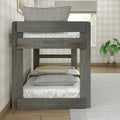 Rustic gray twin-over-twin wooden bunk bed with neutral textured pillows in a cozy plaid wallpaper bedroom with a potted plant