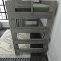 Gray solid-wood bunk bed ladder and safety rails with green bedding in a modern farmhouse kids' bedroom, close-up of loft bed construction