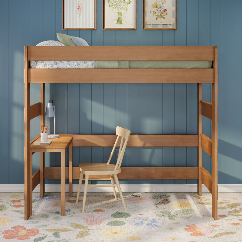 Natural wood kids loft bed with built-in desk and chair against blue paneled wall, floral rug and framed botanical prints