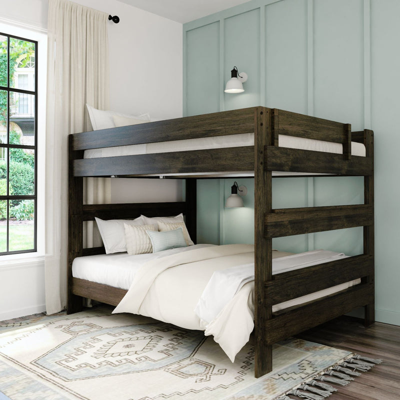 Dark wood twin-over-full bunk bed with white bedding, pale teal board-and-batten accent wall, wall sconce, patterned rug and window with curtains