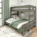 Rustic gray wooden bunk bed with sage green bedding and layered pillows in a modern farmhouse bedroom with wall lamps, patterned rug, and large green curtains.