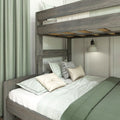 Rustic gray wooden loft bunk bed with mint-green bedding, textured green curtains, patterned throw pillows and a white bedside wall sconce in a modern farmhouse bedroom