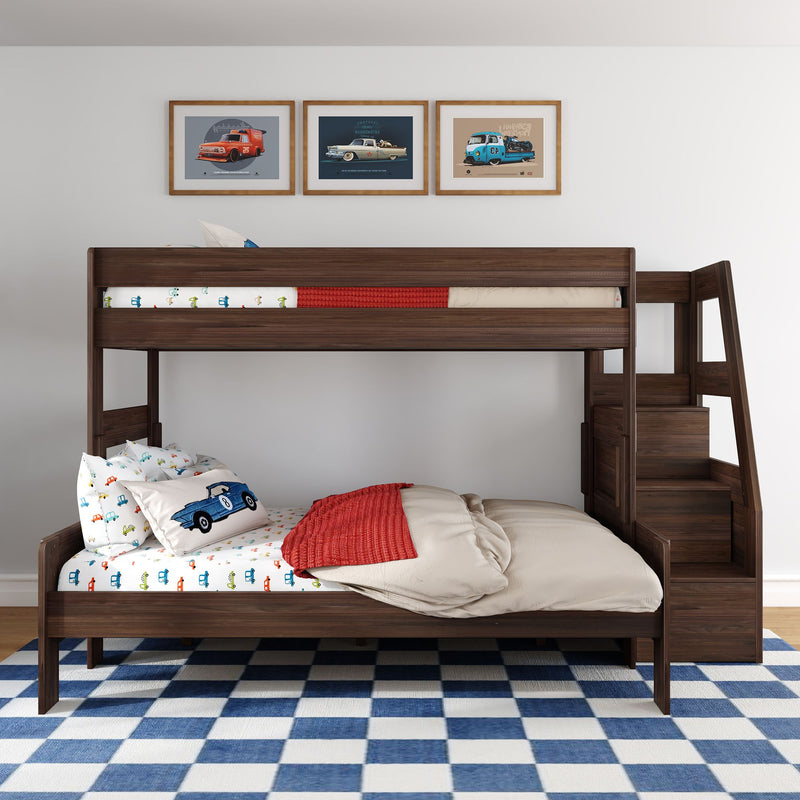 Kids dark wood bunk bed with car-themed bedding and pillows, red throw blanket, framed vintage car prints above and blue checkered rug