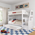 White wooden kids bunk bed with pull-out trundle and staircase storage in a children's bedroom, car-themed bedding and framed vintage car prints, toy car transporter on a blue checkered rug and sheer window curtains