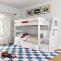 Whitewashed wooden loft bunk bed with storage stairs and car-themed bedding over blue checkered rug, toy cars and framed car prints in a kids' bedroom
