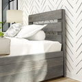 Close-up of modern rustic gray wood bed with slatted headboard, white linens, patterned chevron wallpaper and bedside lamp