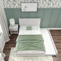 Cozy bedroom with sage green board-and-batten accent wall, light wood bed with trundle, green bedding and bedside lamp